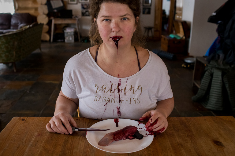 woman stares at camera with tongue cut out lying on plate in front of her for a self-portrait