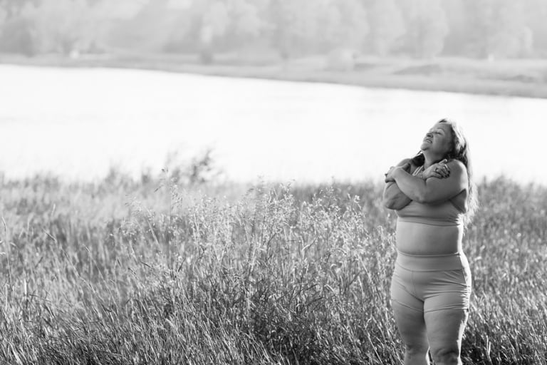 woman embraces herself in nature