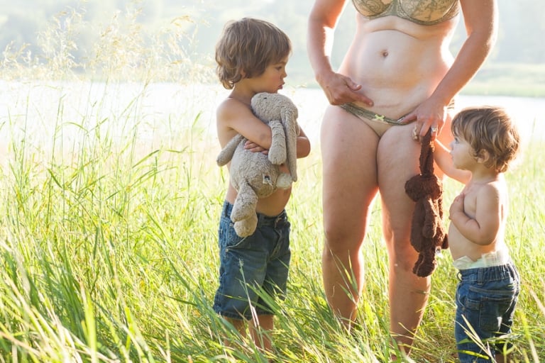 mom of two shows her sons the scar from each of their cesarean births