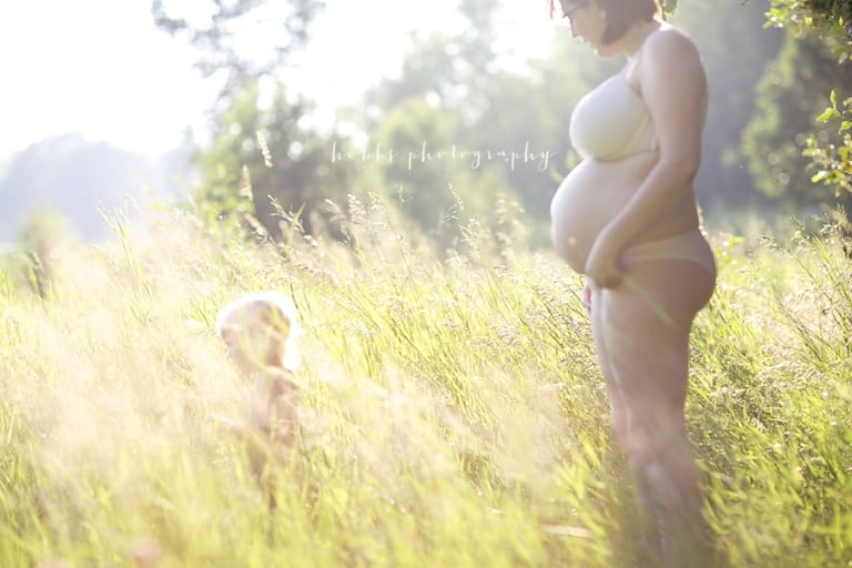 pregnant mom stands in golden light