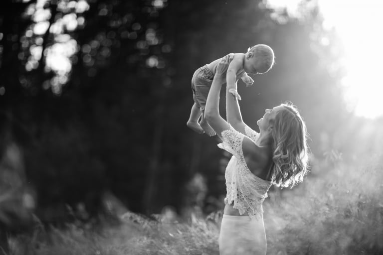 fun lifestyle family session of mom lifting her son above her head