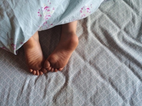 little toes peek out from under a quilt during documentary family session by Edmonton photographer