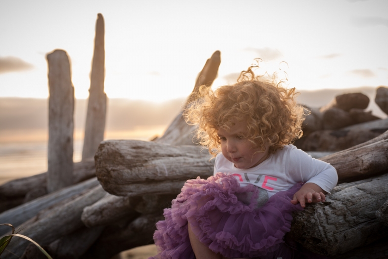 curly hair blows in the wind on Tofino beach in candid picture