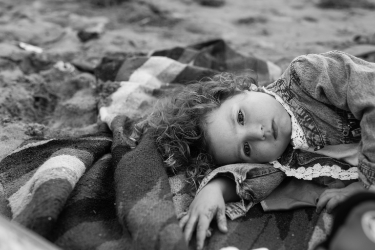 candid photograph of little girl laying on the beach