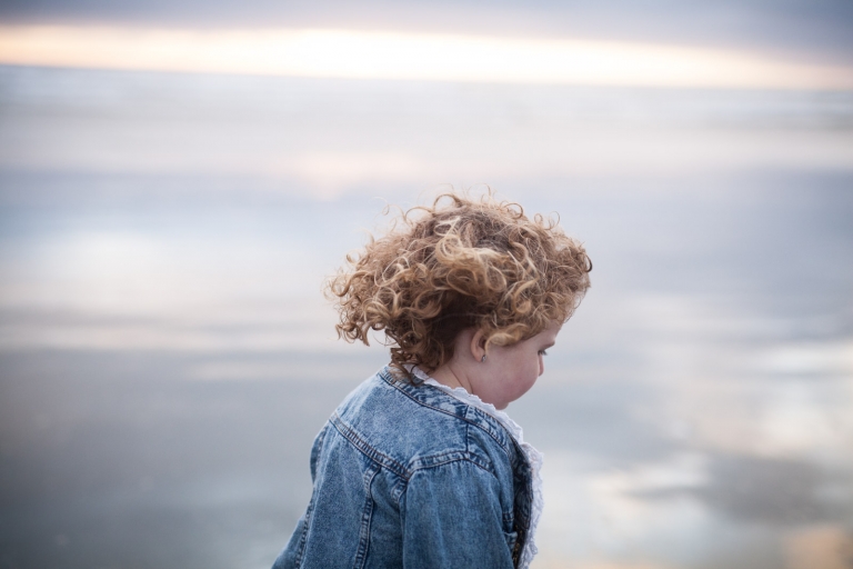 wind blows little girl's hair on Canadian beach for honest portrait