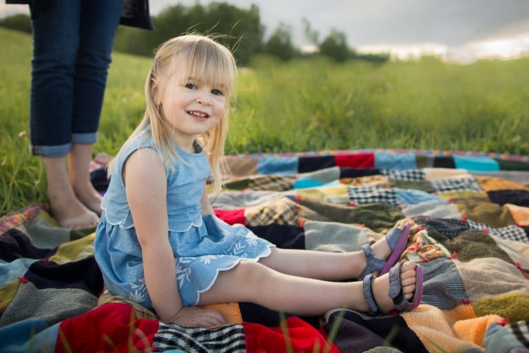 girl sits on vintage quilt during relaxed family photography session