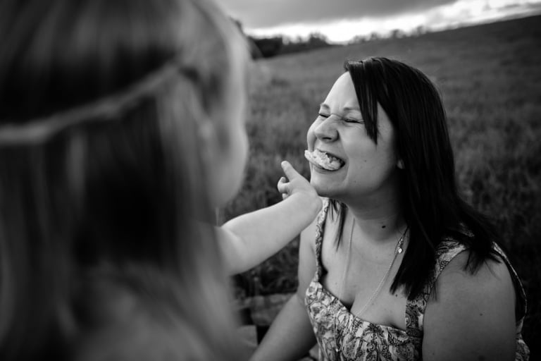 fun black and white portrait of little girl feeding her mom a cookie in Parkland County, Alberta