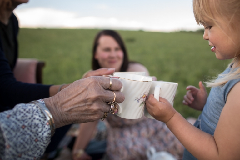 grand daughter and great grandmother have a tea party in a field