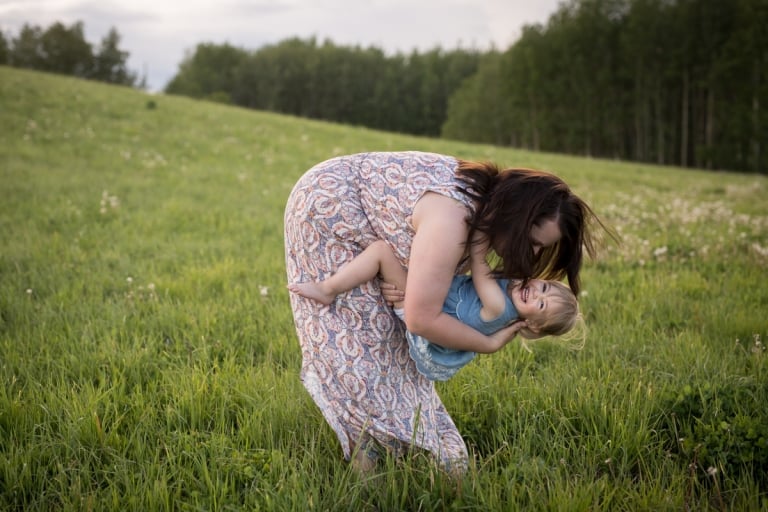 daughter and mom play in field during documentary family photo session