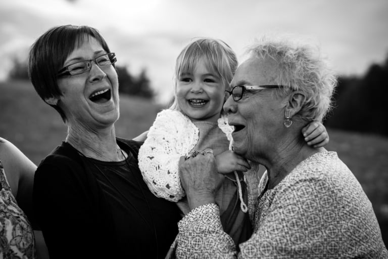 grandma and great grandma laugh with granddaughter in fun edmonton family photography session
