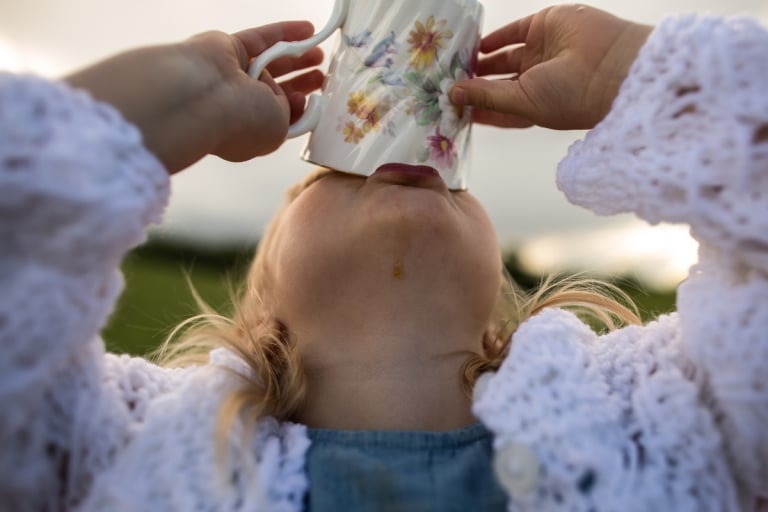 little girl gets every drop of tea out of vintage tea cup during summer photo session