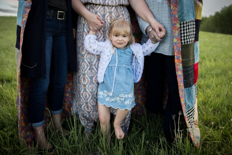 child stands in front of her mother, grandmother and great grandmother unhappy about the long grass on her bare feet