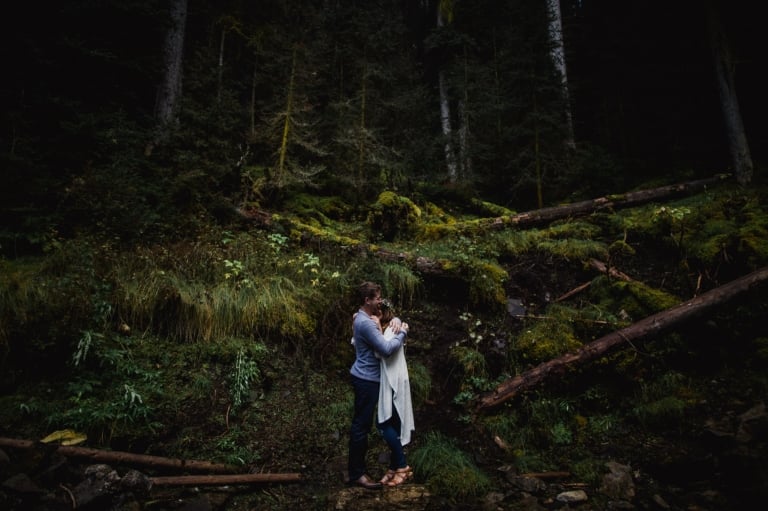boho couple hugs in front of forest