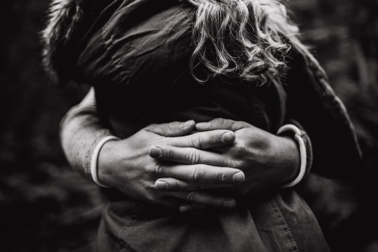 fiance interlaces his fingers behind his future wife's back