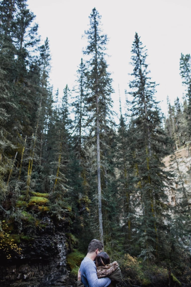 portrait of couple embracing against forest backdrop