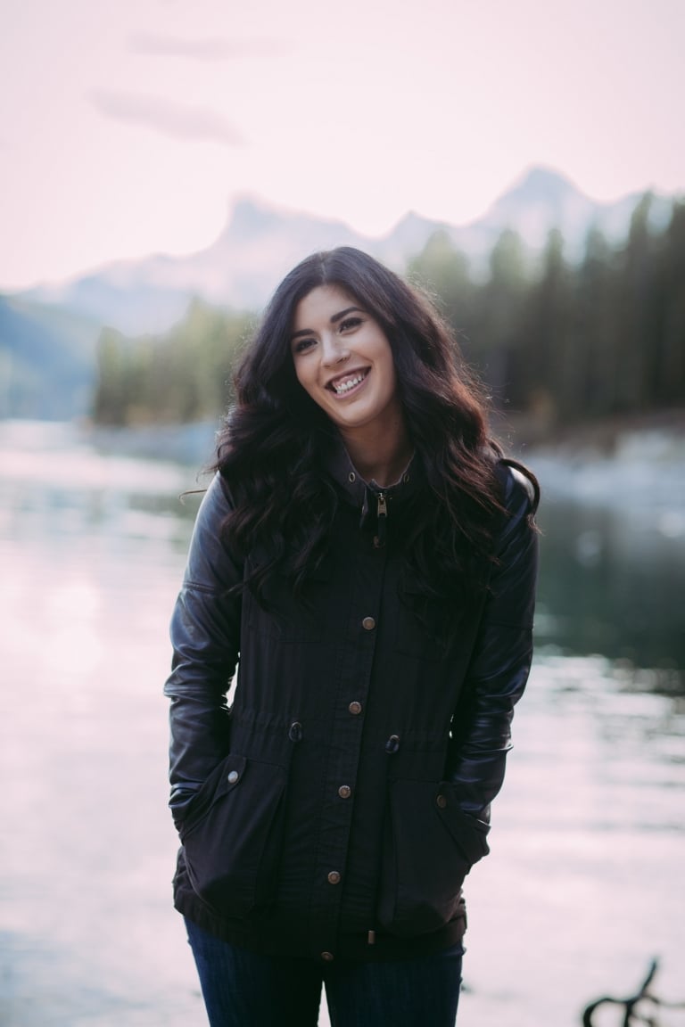fiancee stands on the shore of Lake Minnewanka