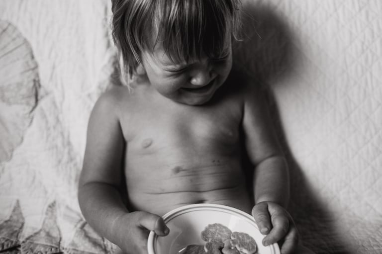 a toddler cries with a snack as mom labours at home