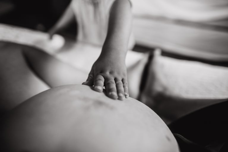 self-portrait during labour by Edmonton birth photographer as a little hand touches her belly