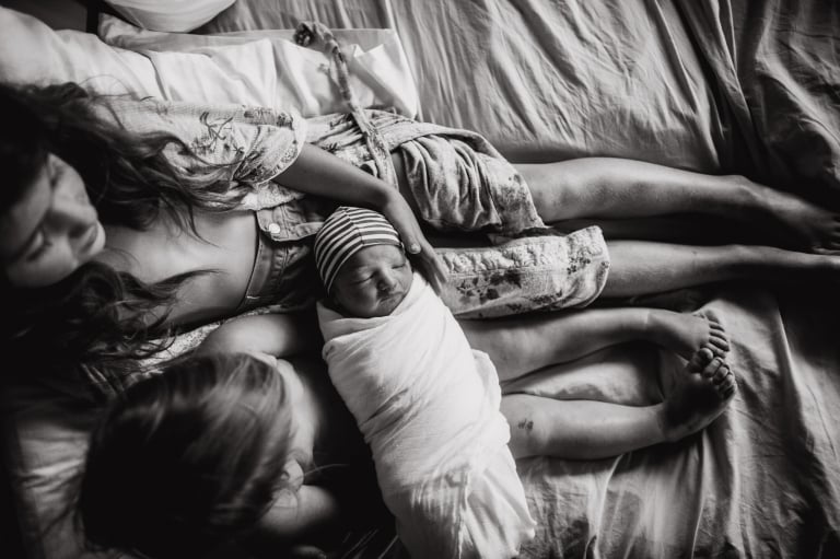 older siblings hold their fresh newborn brother in this photo by Edmonton birth photographer