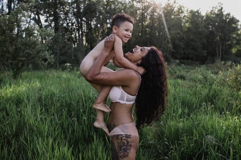 a mother with long black hair lifts her toddler above her