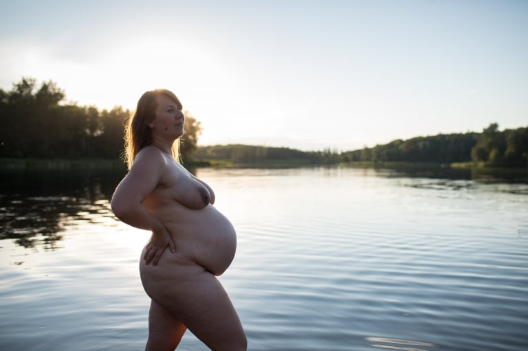 a woman poses nude in the water at 8 months pregnant