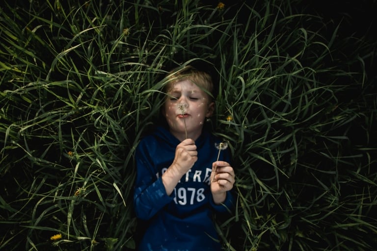 boy blows dandelion fluff during back to school mini sessions