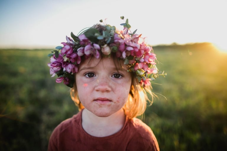 a grubby toddler wears flower crown during golden hour photo session