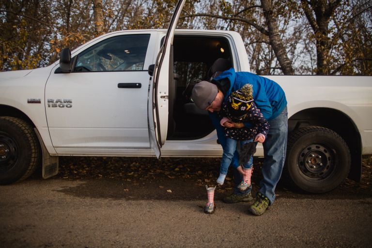 dad lifts child into white truck