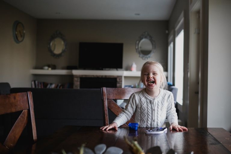 little girl laughs at table