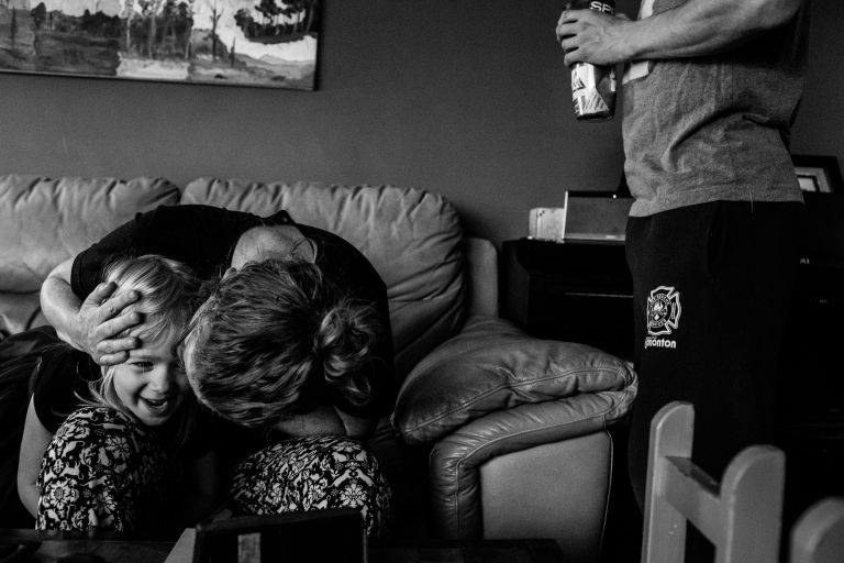 a mom kisses her daughter in their living room in Edmonton