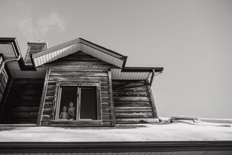 black and white picture of kids looking out upstairs window