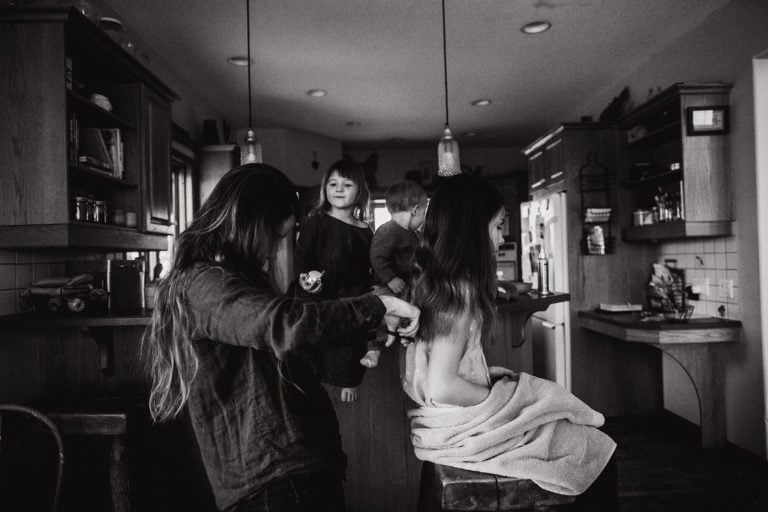 mom trims her daughter's hair in the kitchen
