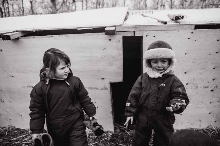 twins stand in corral in winter clothes