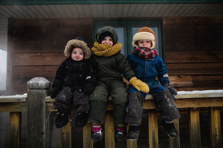 siblings sit outside during Alberta winter