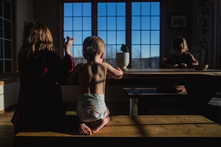 baby sits at table eating breakfast