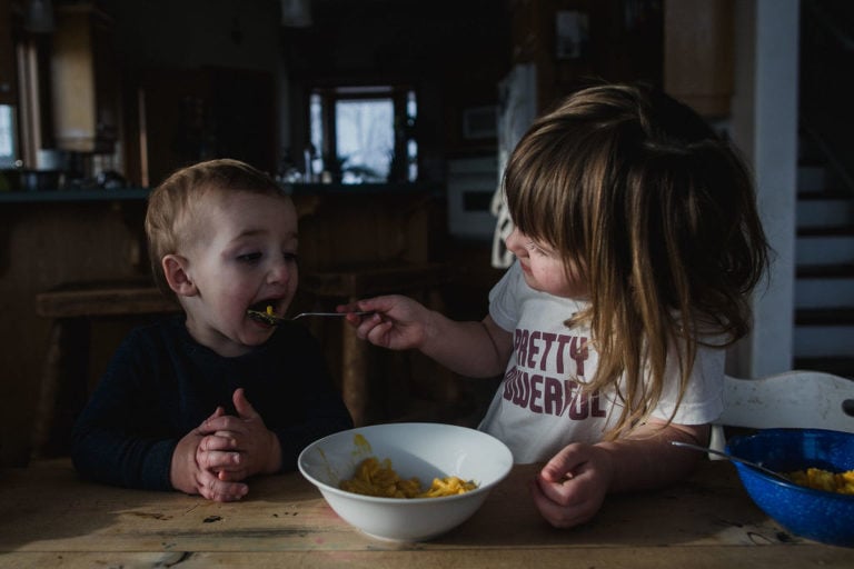 big sister feeds baby brother lunch