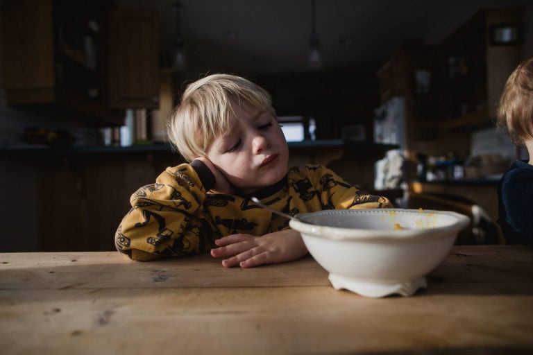 little boy pouts at kitchen table