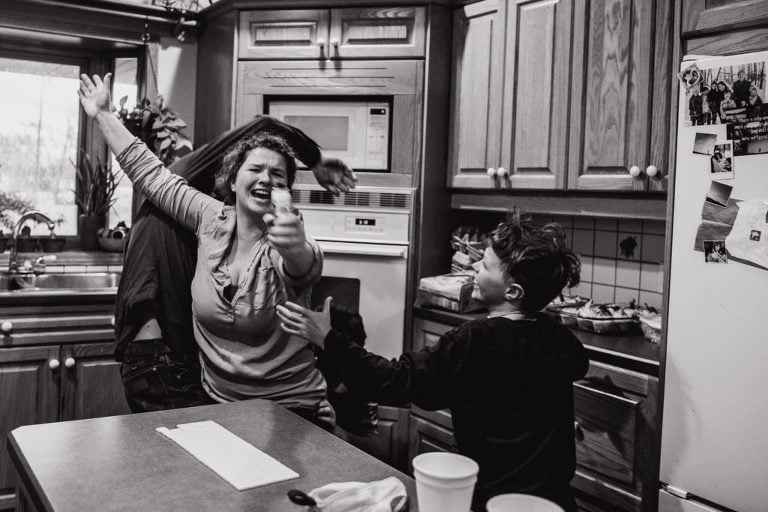 family wrestles in kitchen