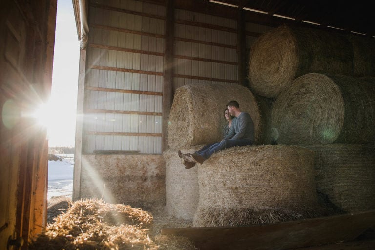 couple sits together in the hay shed as sun streams in