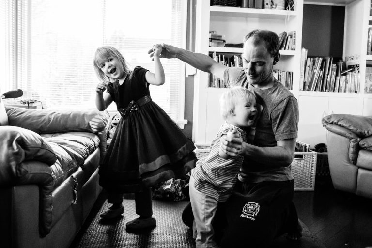 dad dances with both his daughters in their Edmonton family home