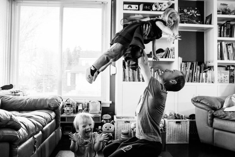 two little girls delight in spending time with their dad playing in the living room