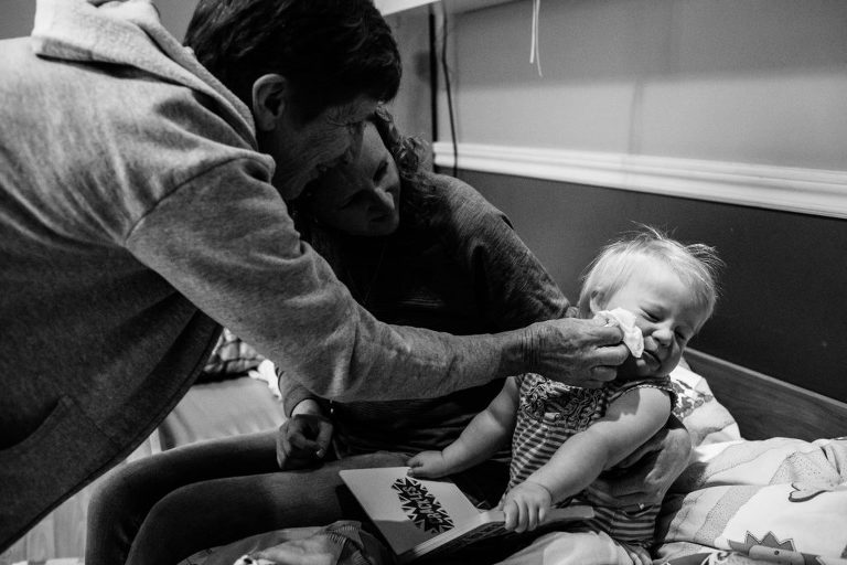 grandma wipes a sick toddler's face during story time