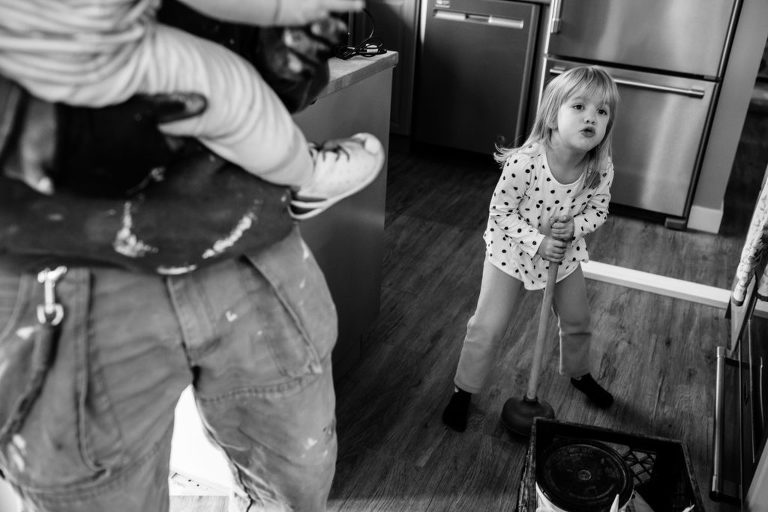 little girl sings a song and keeps time with a toilet plunger in photo by Hobbs Photography