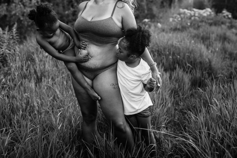 black and white portrait of a toddler squeezing her mom's squishy belly near Stony Plain, Alberta