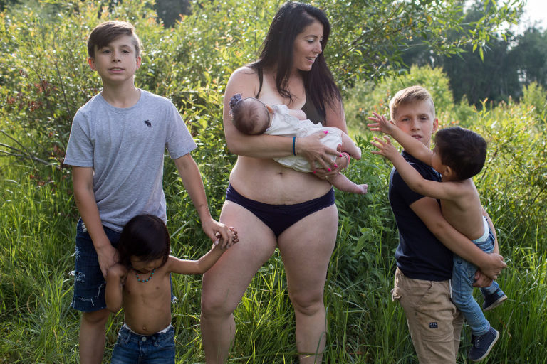 foster son reaches for his mother during an outdoor portrait with his siblings